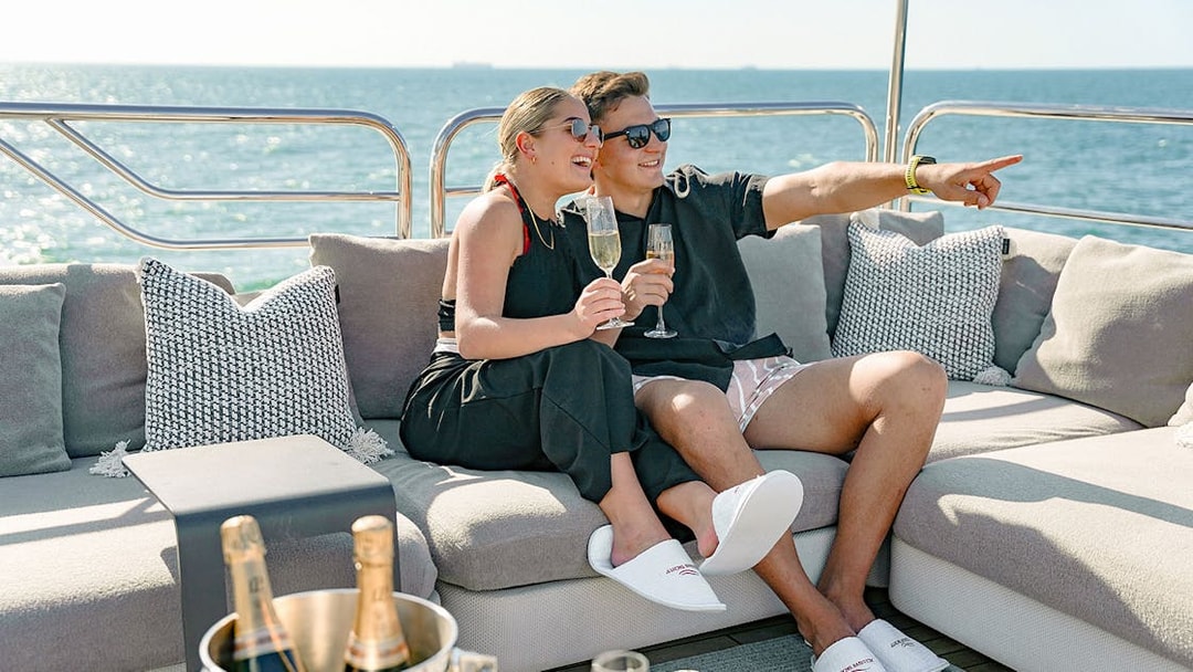 Couple enjoying champagne on a Sunseeker superyacht with ocean view.