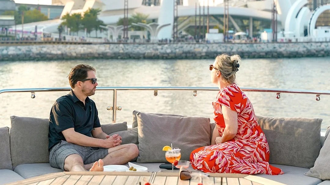 Couple enjoying drinks on a Sunseeker superyacht with waterfront view.