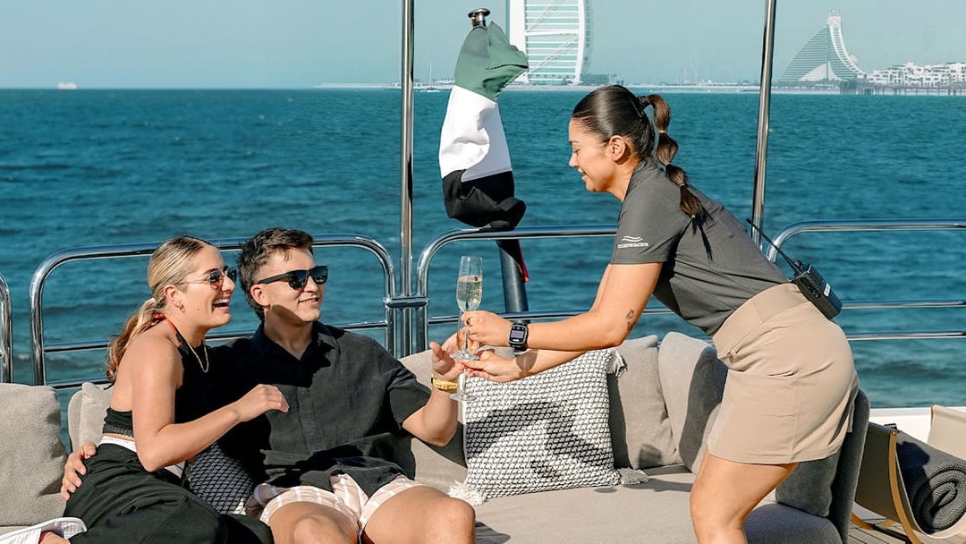 Couple enjoying drinks on a Sunseeker superyacht with Dubai skyline in the background.