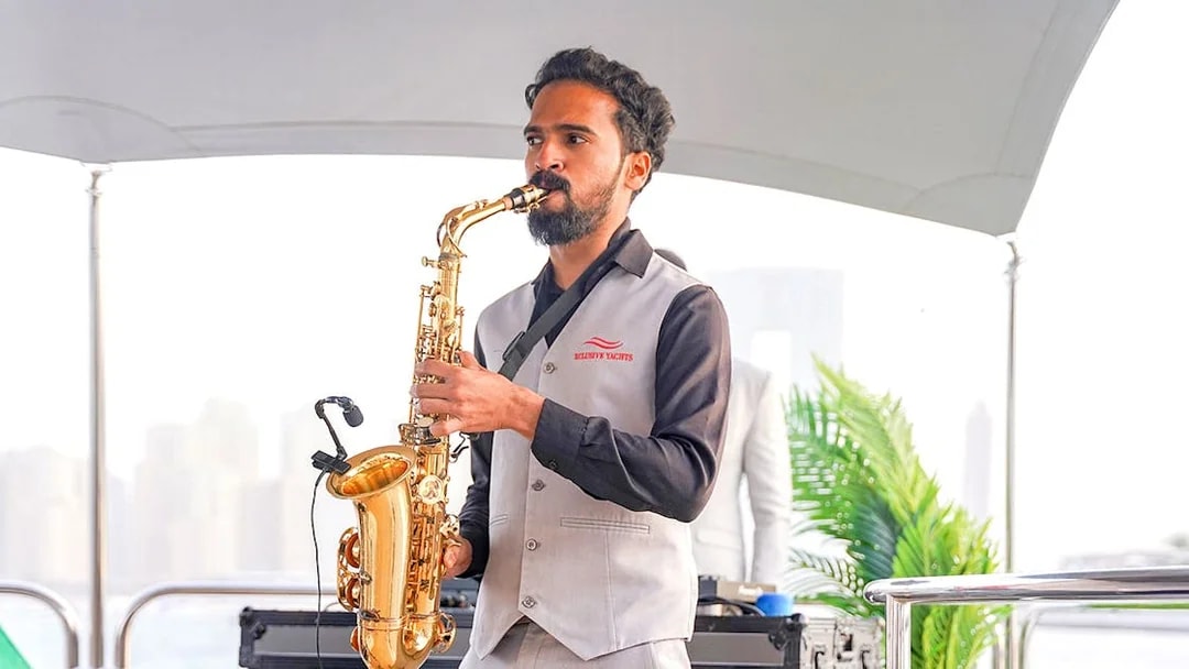 Saxophonist performing on Sunseeker superyacht with city skyline in background.