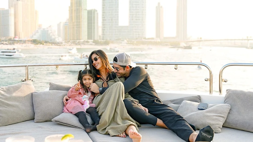Family relaxing on a Sunseeker superyacht with city skyline in the background.