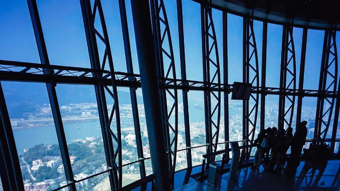 View from Macau Tower observation deck overlooking city and harbor.