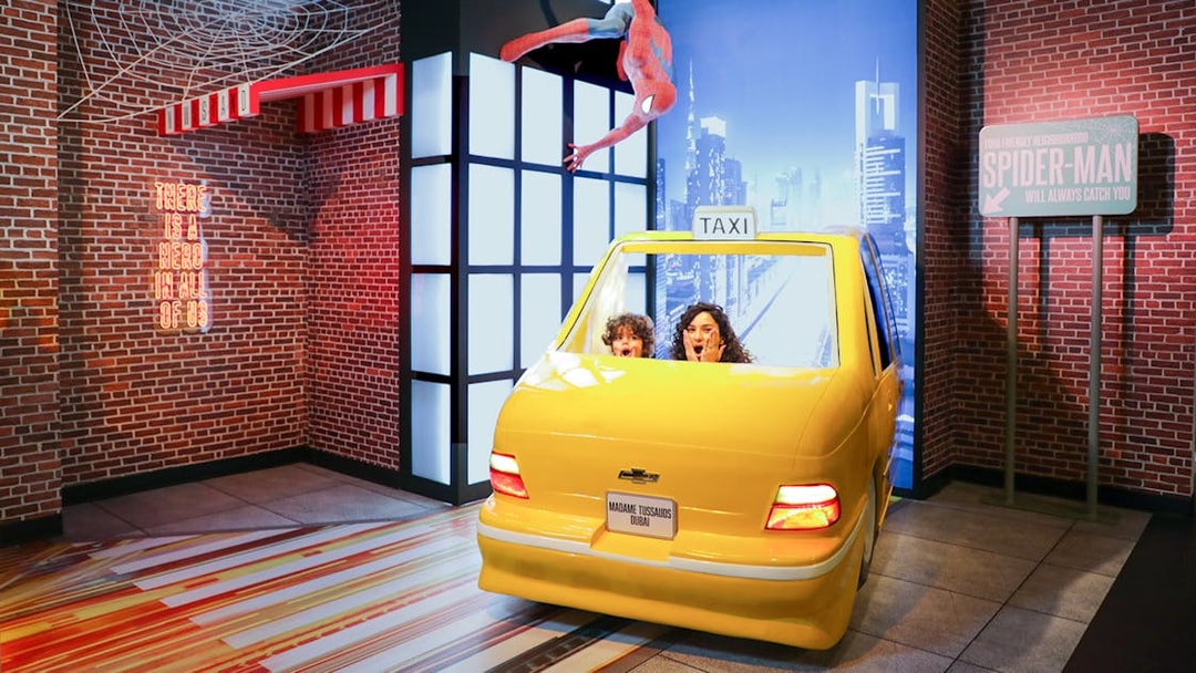 Spider-Man figure above yellow taxi at Madame Tussauds Dubai movie set.