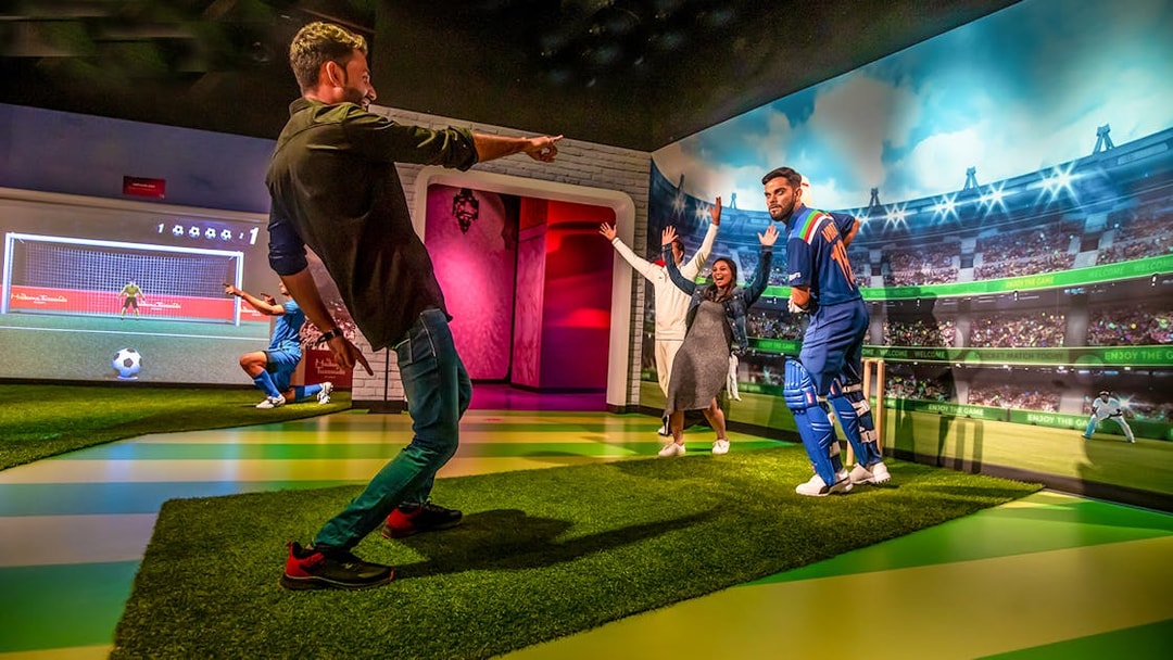 Visitors interacting with a cricket player wax figure at Dubai Madame Tussauds.