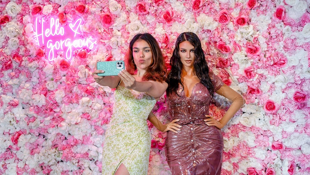 Woman taking selfie with wax figure at Madame Tussauds, New York.