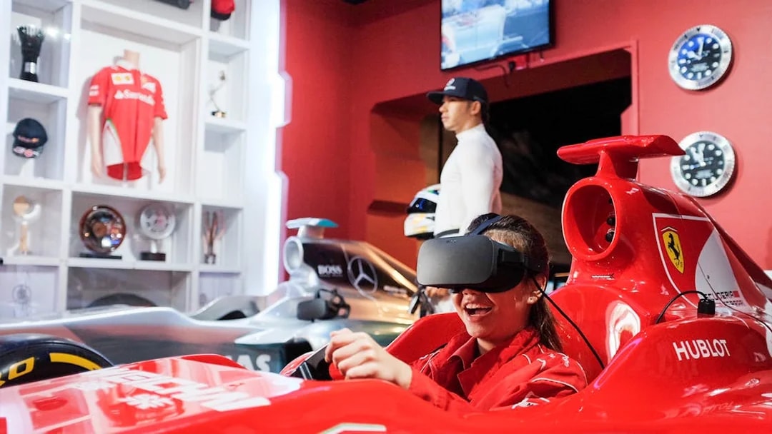 Visitor enjoying a VR racing experience at Madame Tussauds Singapore with wax figure in background.
