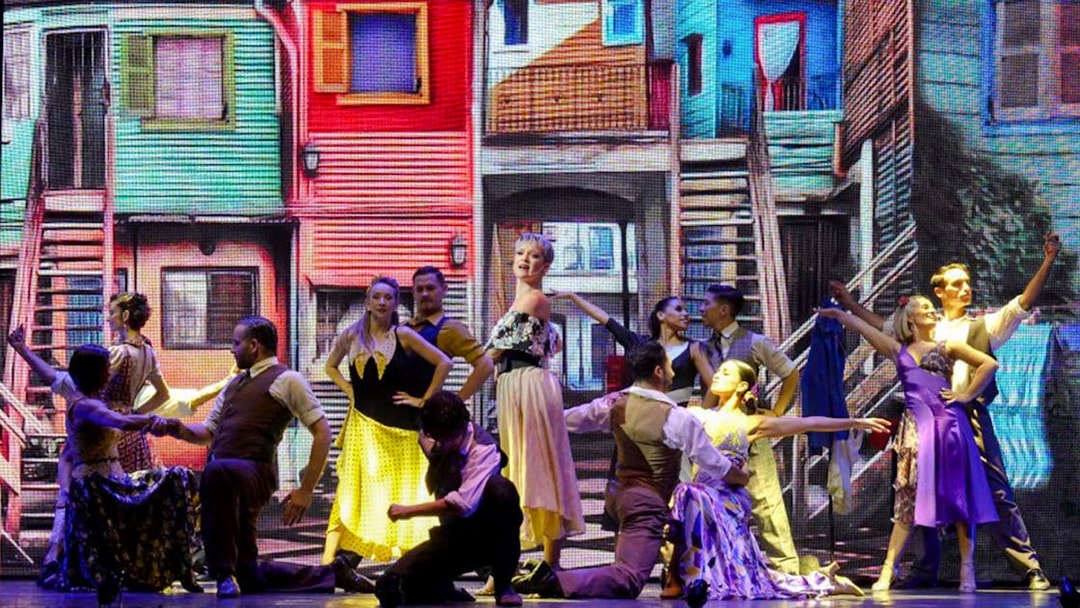 Dancers performing at Madero Tango Show with colorful La Boca backdrop.