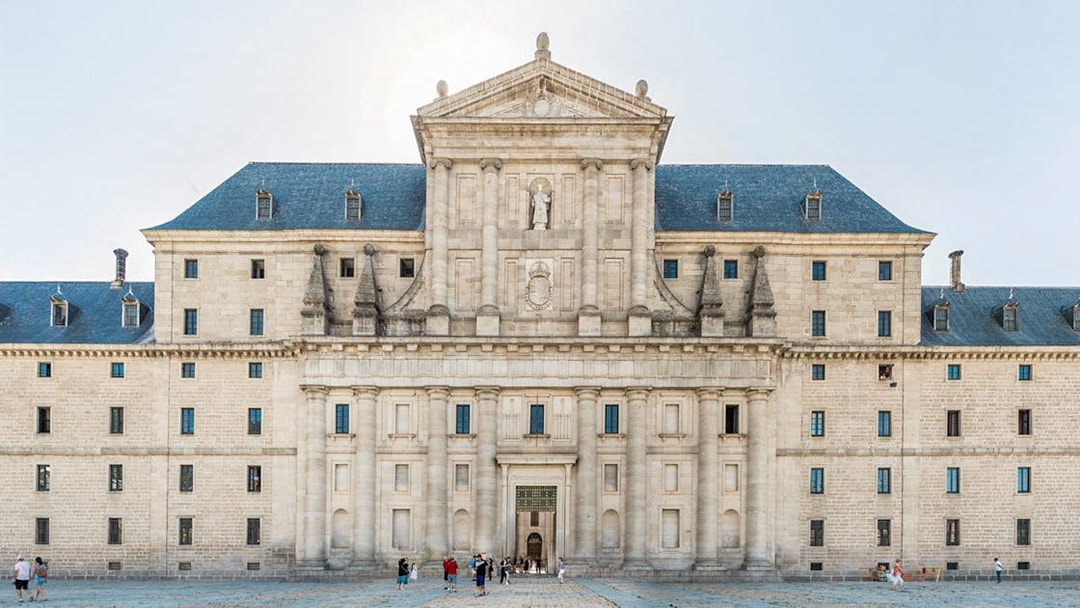 El Escorial courtyard with visitors in front of the historic facade, Spain.