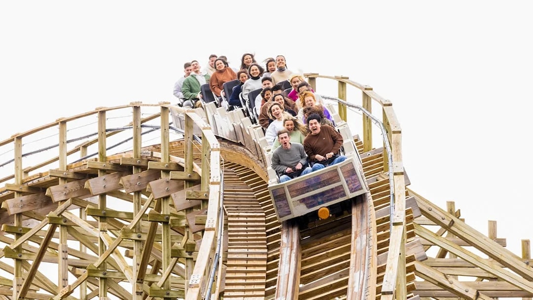 Riders on Coaster Express at Parque Warner Madrid descending a wooden track.