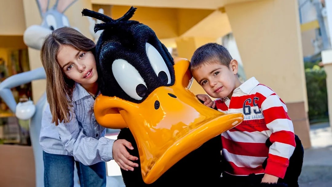 Children posing with a cartoon character at a theme park.