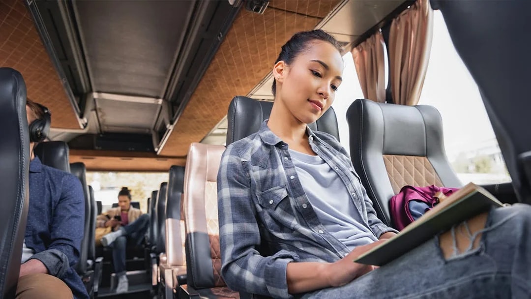 Passengers seated inside an AC transfer bus for the Golden Circle & Glacier Snowmobile Tour.