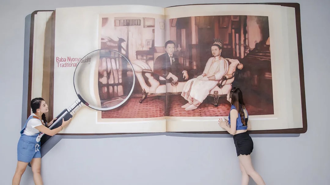 Visitors interact with a 3D art installation of a magnified book at Magic Art 3D Museum.