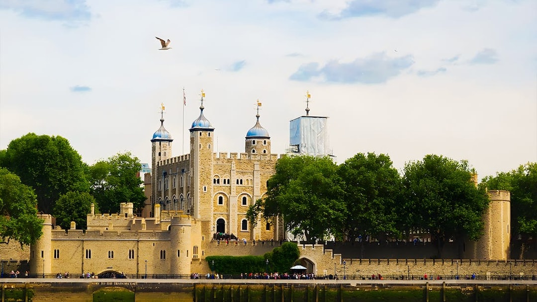 Tower of London's White Tower with surrounding trees and river view.