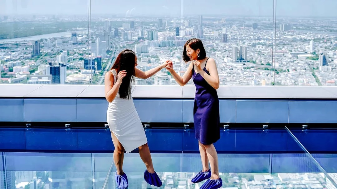 Friends enjoying the glass floor at Mahanakhon SkyWalk, Bangkok, Thailand.