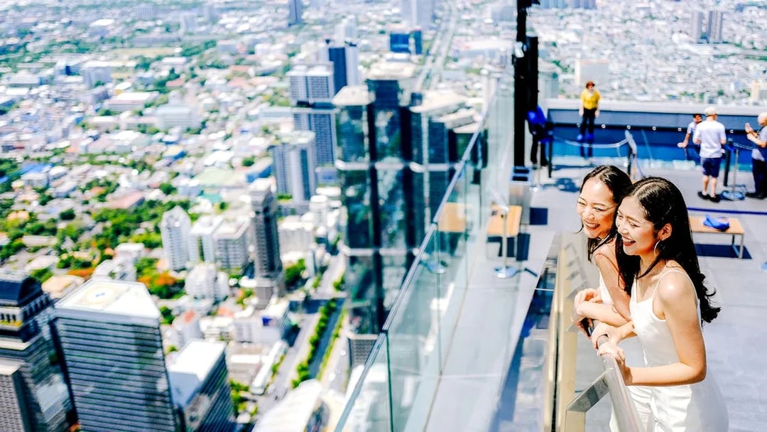 Friends enjoying the view from Mahanakhon SkyWalk in Bangkok, Thailand.