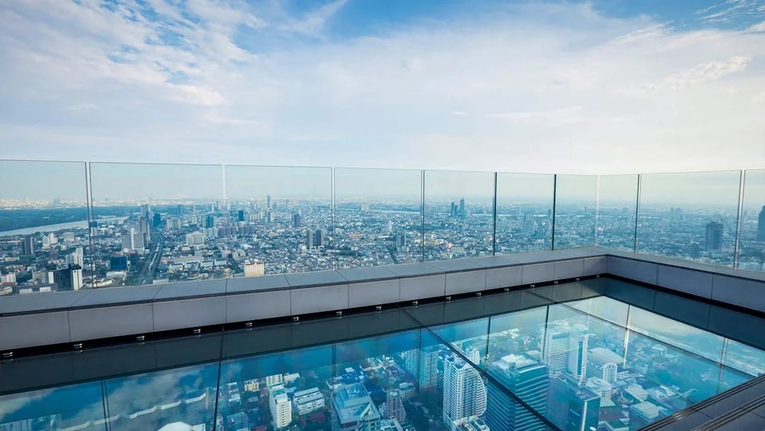 Mahanakhon SkyWalk glass floor with panoramic view of Bangkok cityscape.