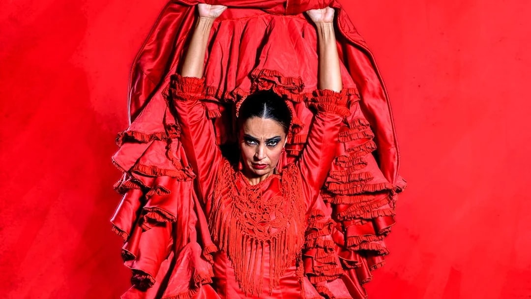 Flamenco dancer in red dress performing at Esencia espectáculo flamenco.