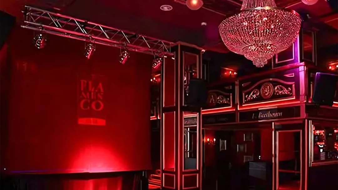 Flamenco stage with red lighting and chandelier at Málaga Club.