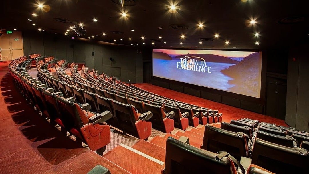 Theater interior for The Malta Experience audio-visual show, featuring a large screen and seating.