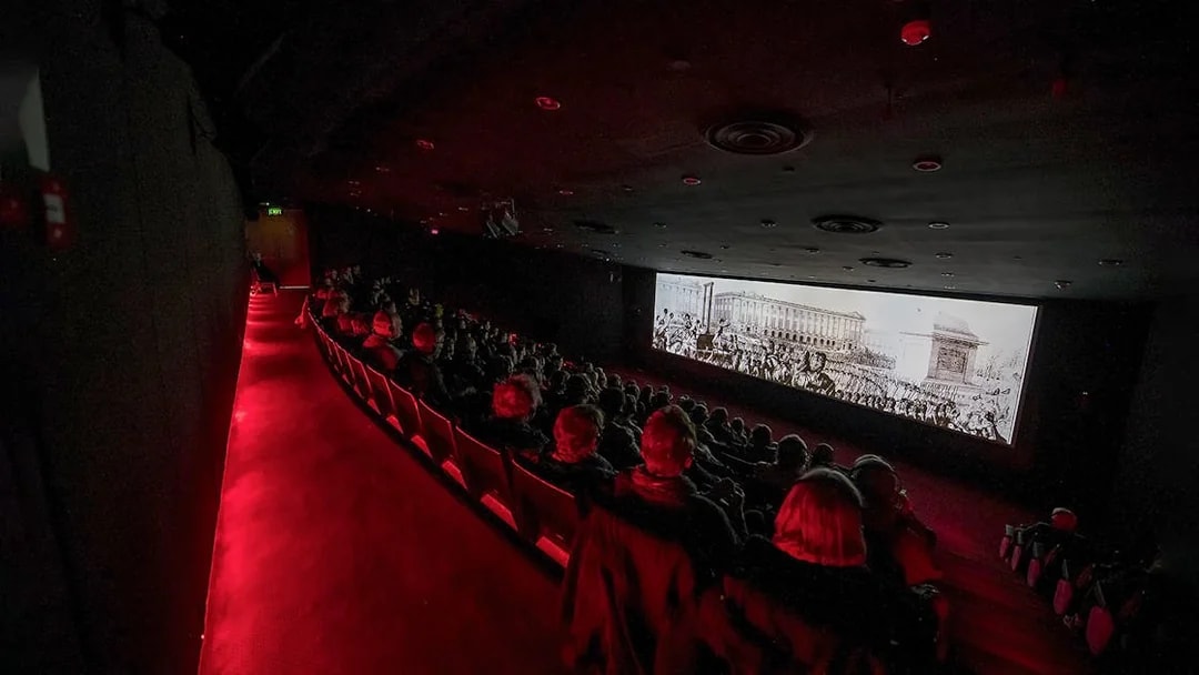 Visitors watching The Malta Experience audio-visual show in a dark theatre.