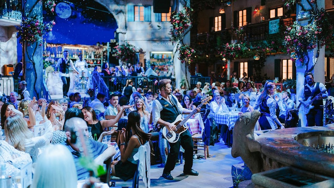 Guests enjoying live music at Mamma Mia! The Party in a vibrant Greek taverna setting.