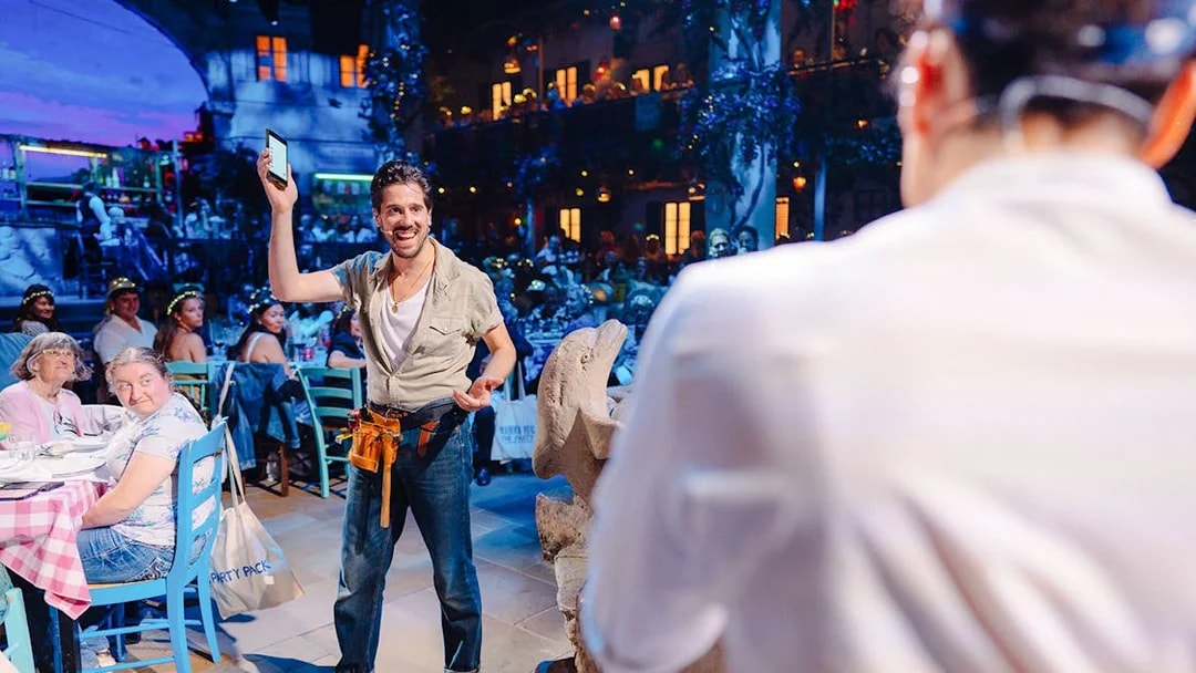 Man engaging audience at Mamma Mia! The Party event, lively atmosphere.
