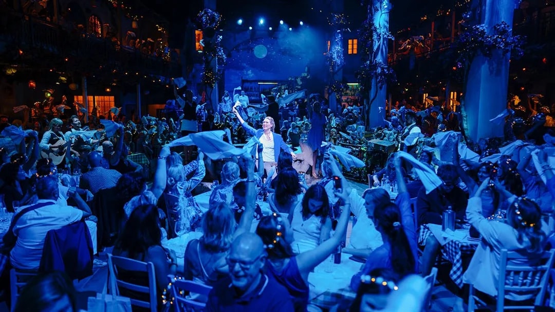 Crowd enjoying Mamma Mia! The Party with performers and lively atmosphere.