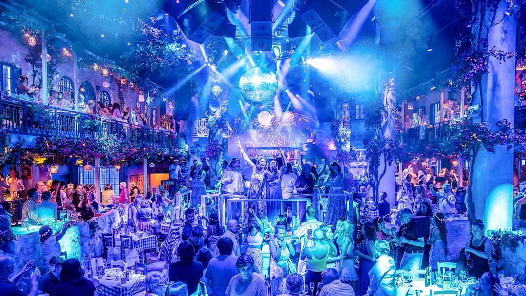 Guests enjoying Mamma Mia! The Party with vibrant lights and lively atmosphere.