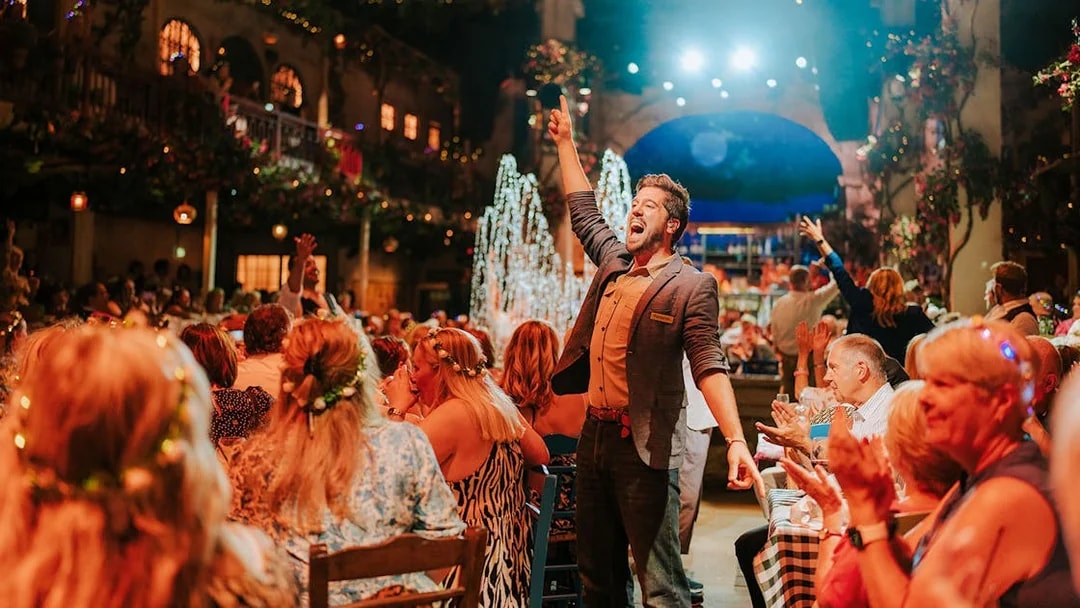 Performer engaging audience at Mamma Mia! The Party with festive atmosphere.