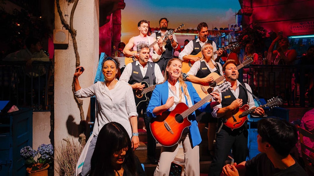 Performers playing guitars and singing at Mamma Mia! The Party event.