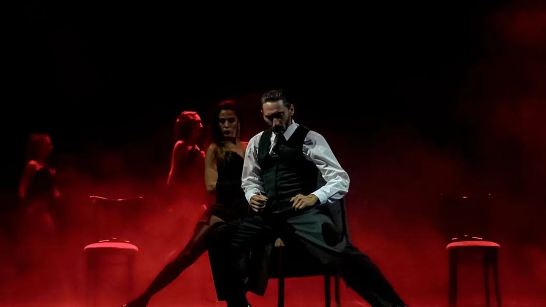 Dancers performing at Mansión Tango Show with dramatic red lighting.