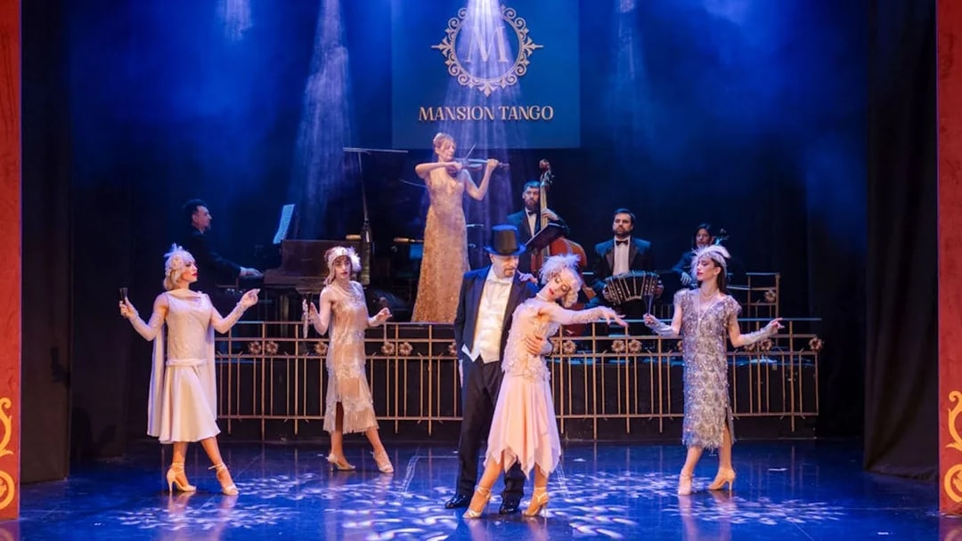 Dancers performing at Mansión Tango Show with live musicians on stage.