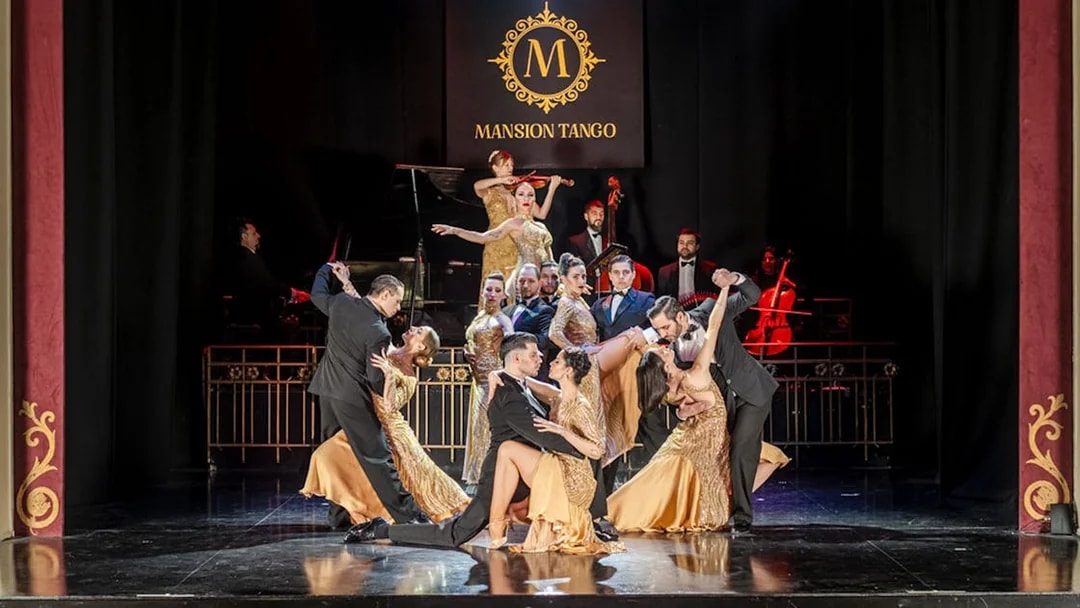 Dancers performing at Mansión Tango Show with musicians in the background.