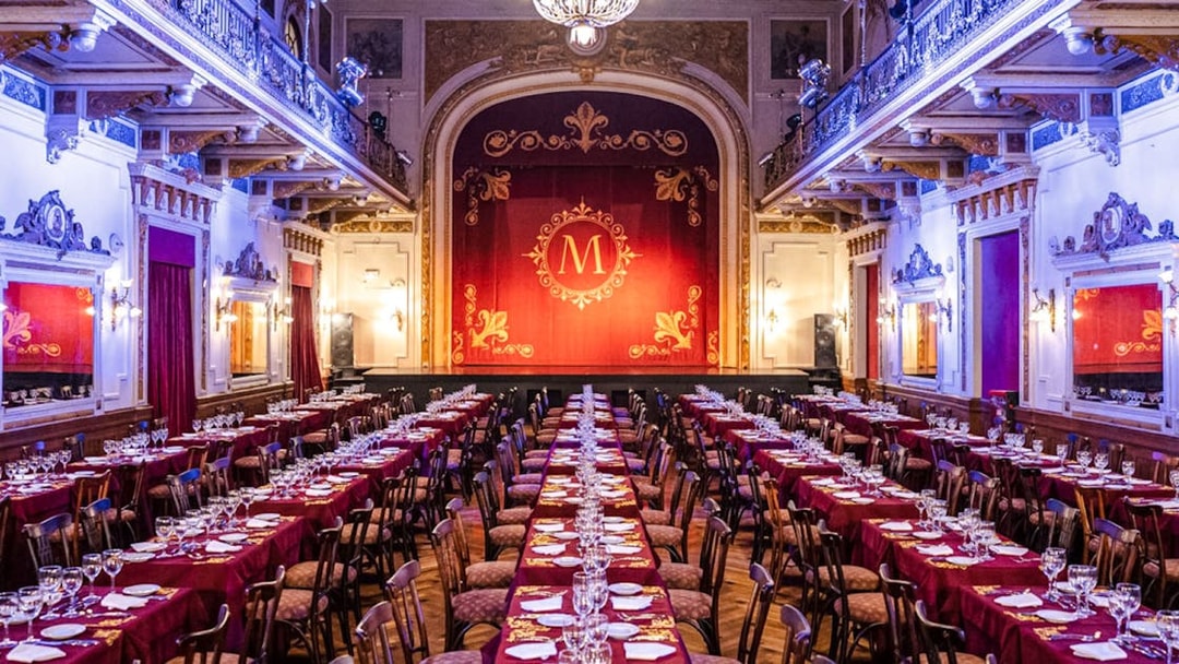 Elegant theater setup for Mansión Tango Show with red drapes and ornate decor.
