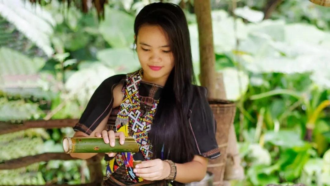 Woman in traditional attire demonstrating bamboo craft at Mari Mari Cultural Village.