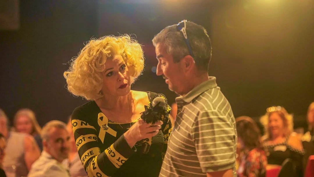 Performer interacting with audience member during "Marriage Can Be Murder" show.
