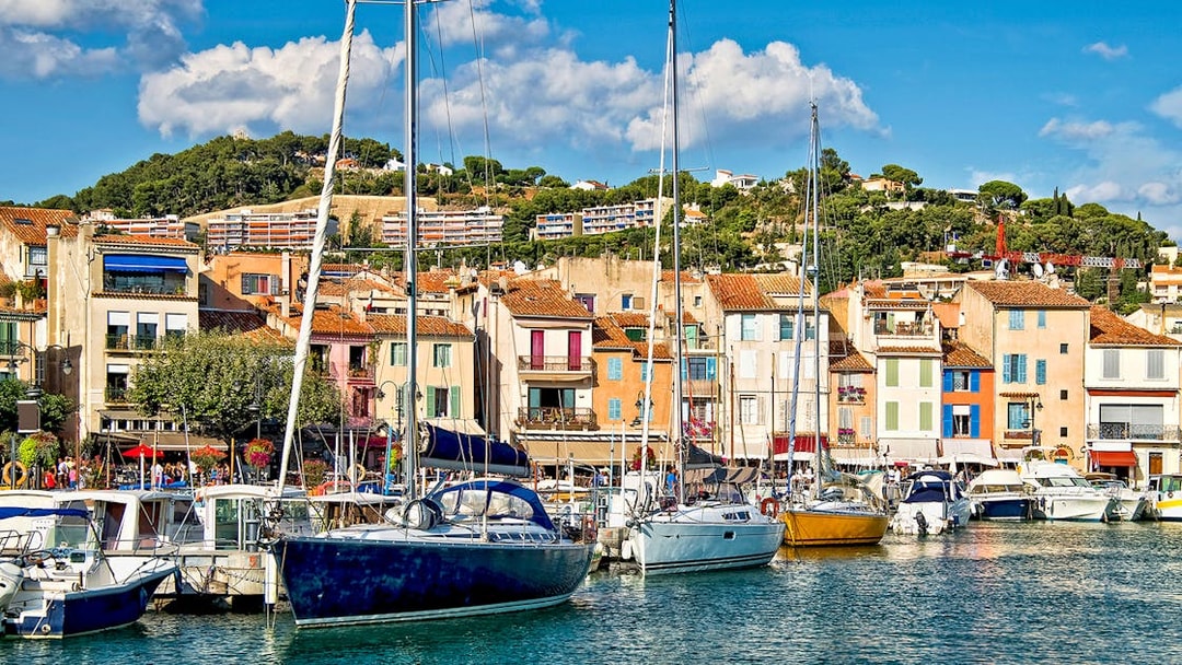 Boats docked at the colorful harbor of Cassis, France, with hillside buildings in the background.