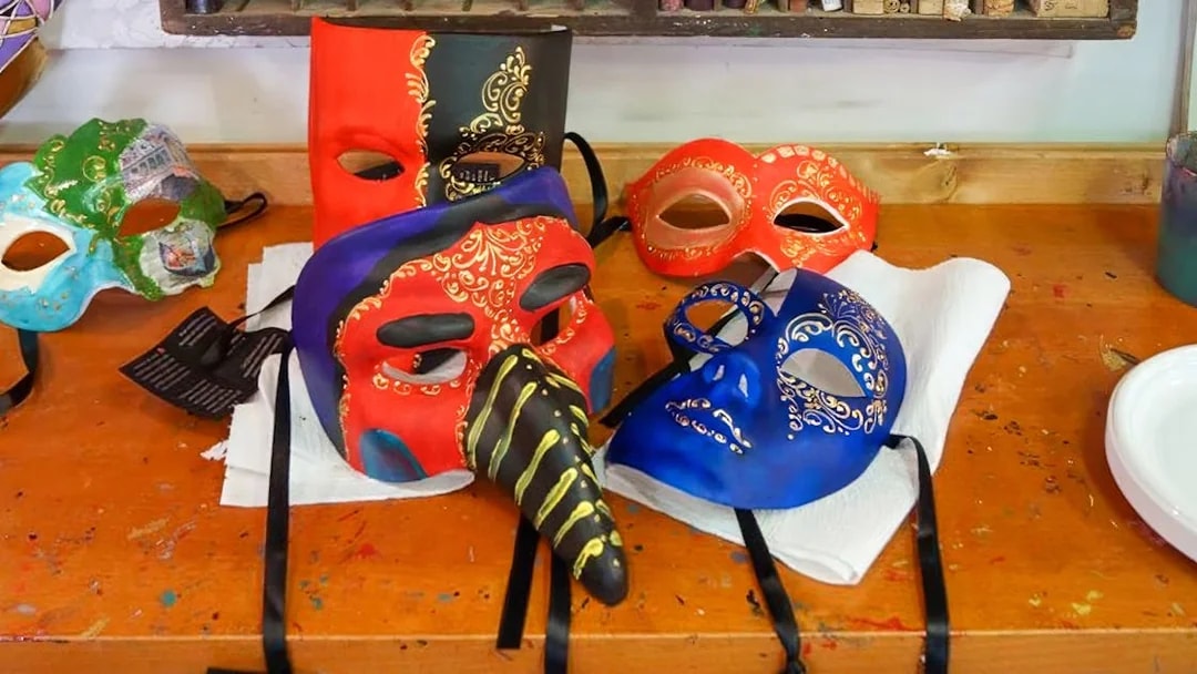 Colorful Venetian masks on a workshop table for a mask painting activity.