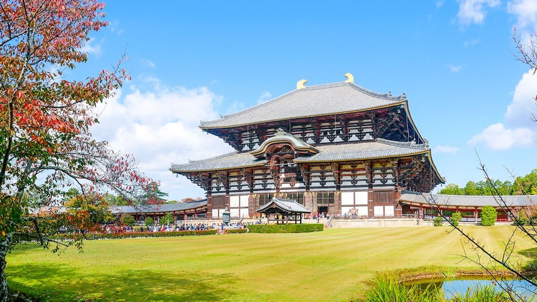 Tōdai-ji Temple in Nara, Japan with autumn foliage and a clear blue sky.