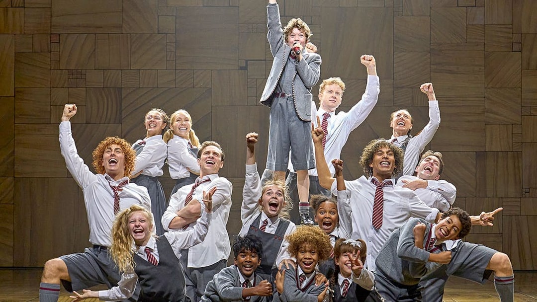 Cast of Matilda The Musical performing on stage with raised fists.