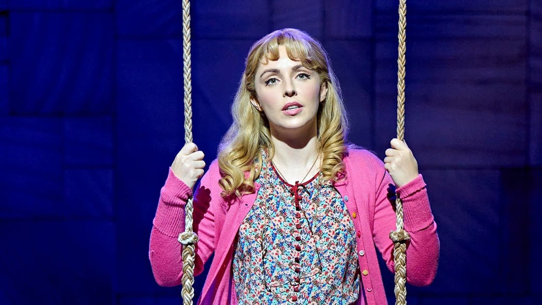 Performer on stage in Matilda The Musical holding a swing rope.