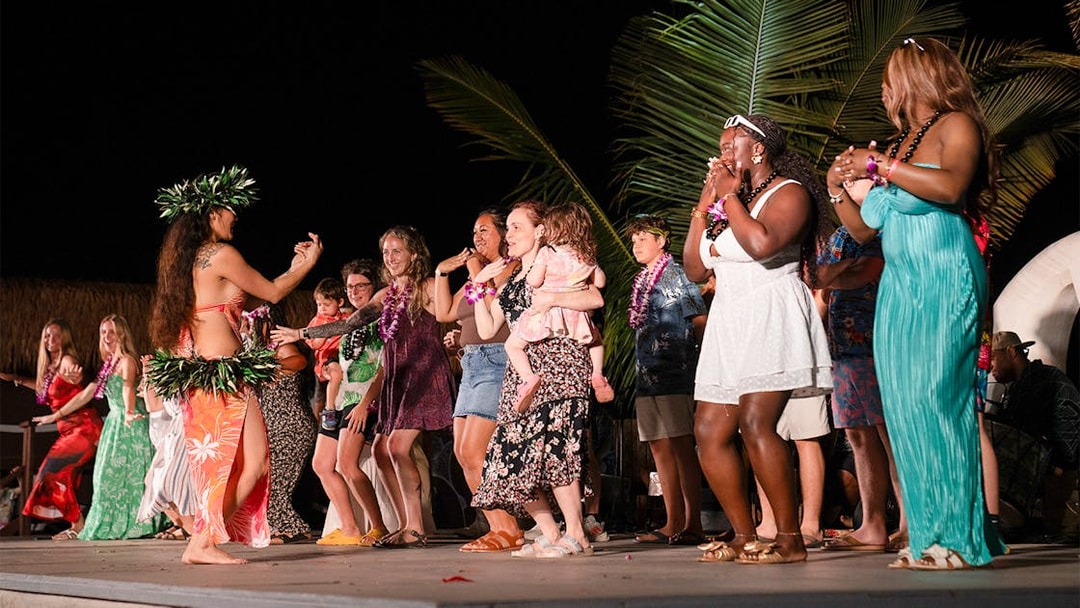 Guests dancing with performers on stage at Mauka Warriors Luau cultural show.