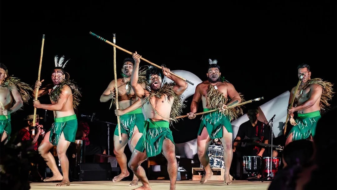 Performers with traditional attire and sticks on stage at Mauka Warriors Luau cultural night show.