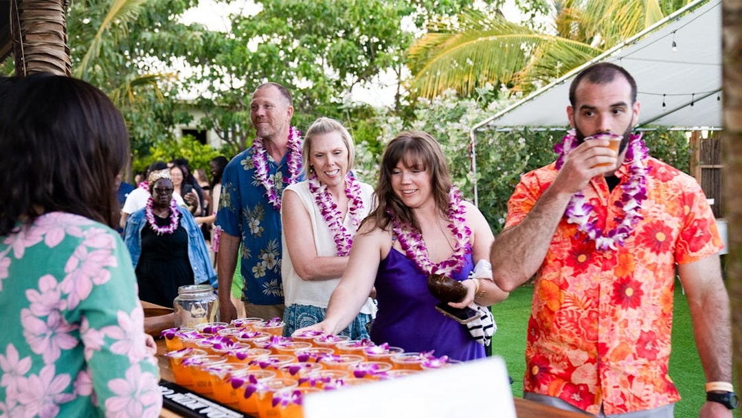 Guests receiving welcome drinks at Mauka Warriors Luau entrance.