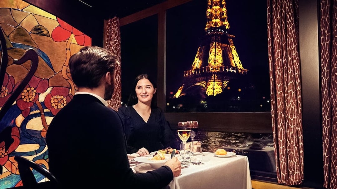 Couple dining on Maxim's Seine River Cruise with Eiffel Tower view.