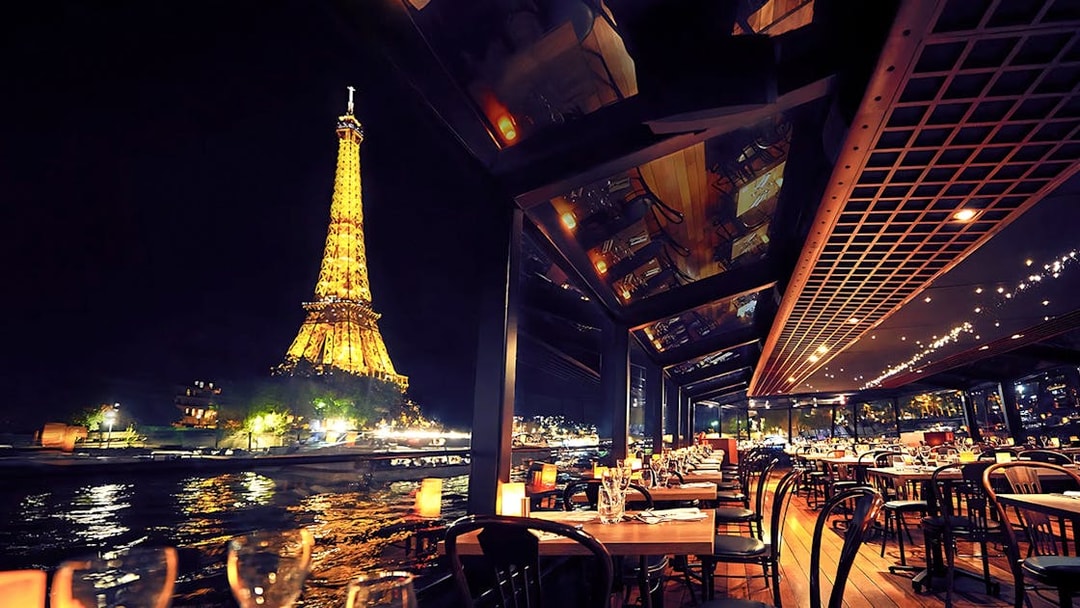 Seine River cruise dining with Eiffel Tower view at night, Paris.