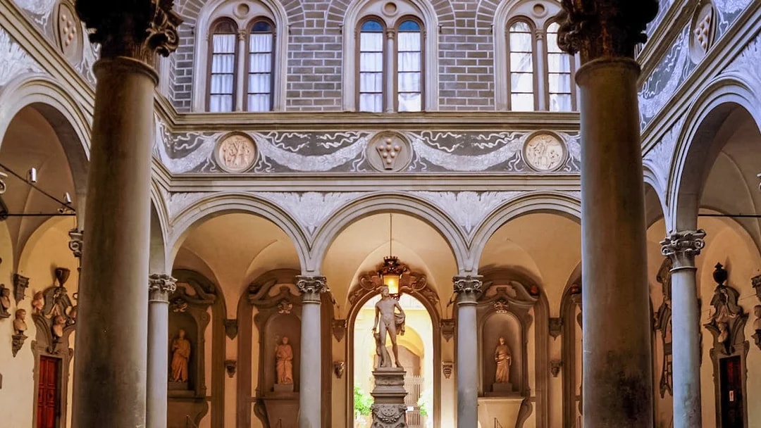 Palazzo Medici Riccardi courtyard with classical statues and ornate arches in Florence, Italy.