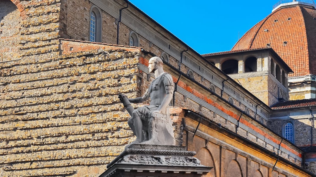 Statue in San Lorenzo Square, Florence, with historic architecture in the background.