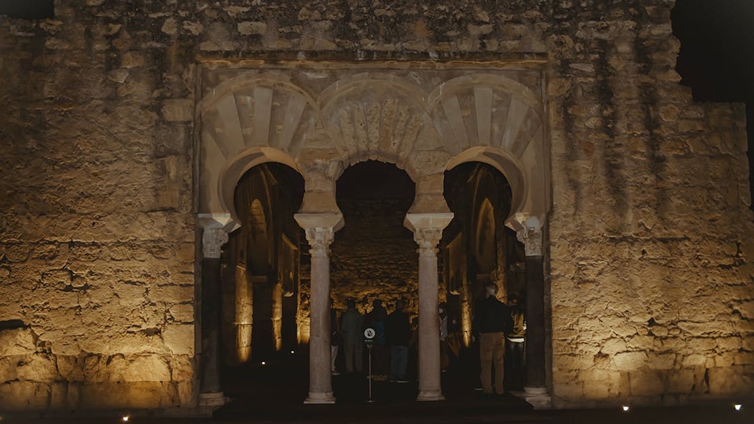 Guided group exploring illuminated arches of Medina Azahara at night.