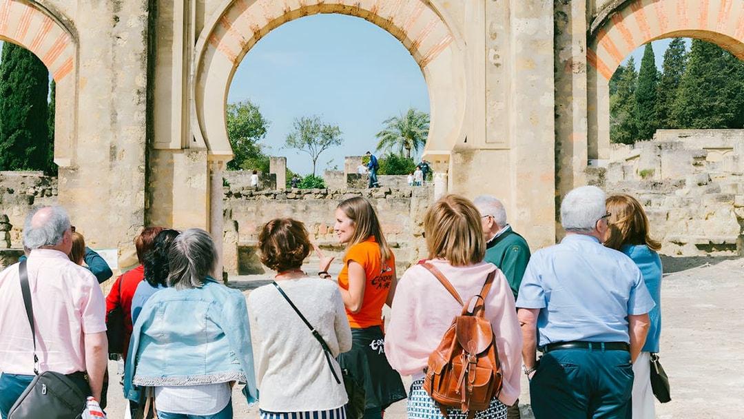 Guided group tour at Medina Azahara, Córdoba, with historical arches in the background.